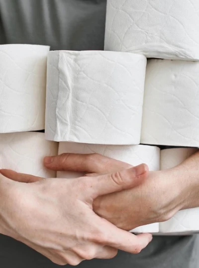 Pessoa segurando vários rolos de papel higiênico contra o peito.